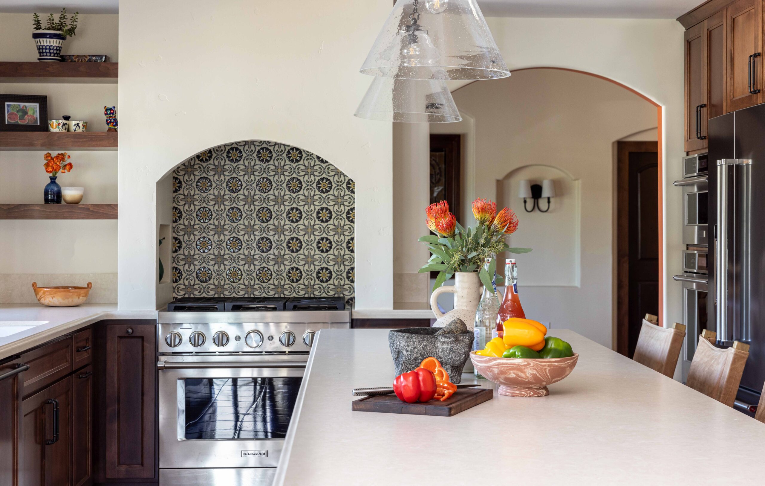 Spanish style kitchen with arched range hood and accent tiles.