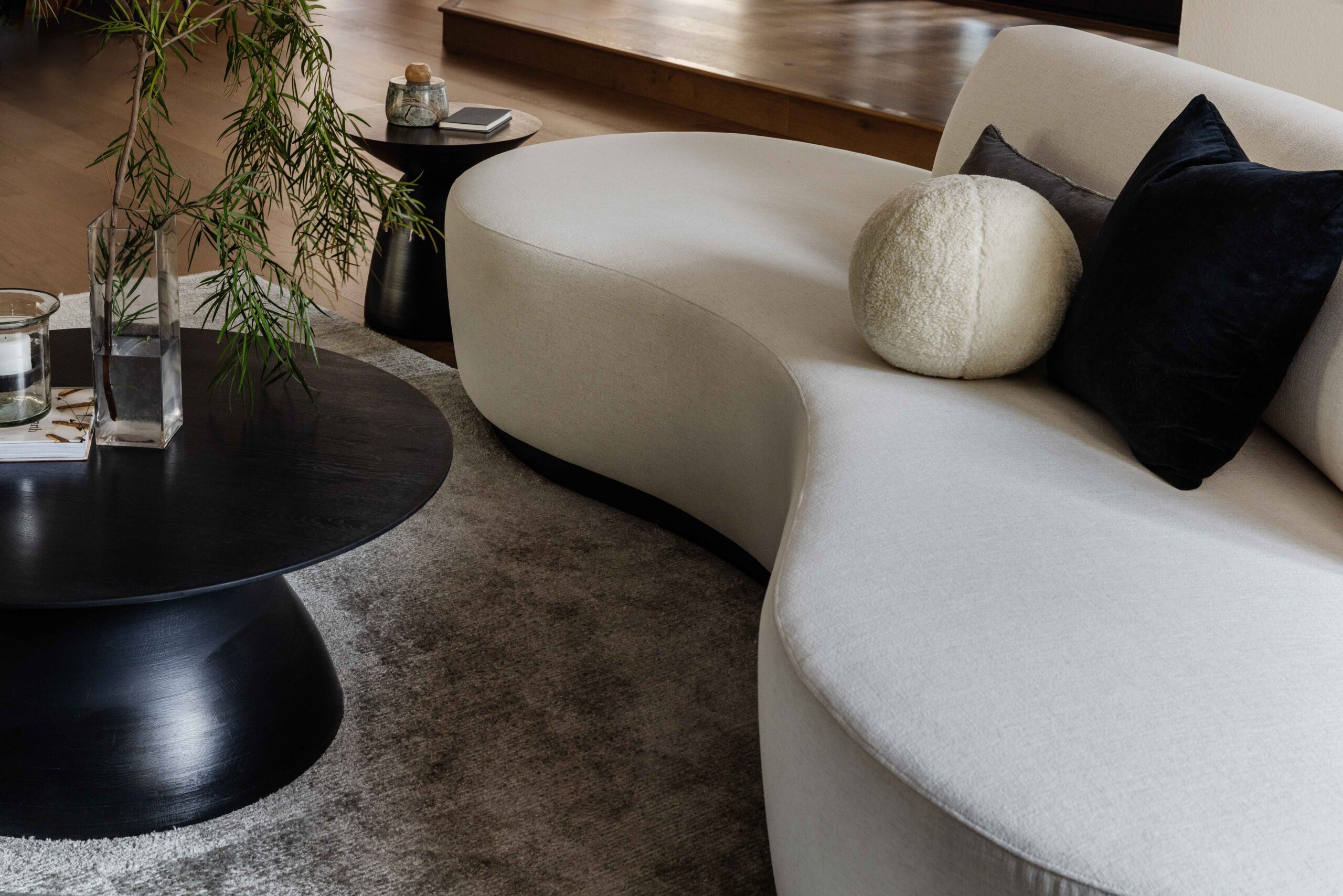 Everyday Luxury Living Room Curved White contemporary sofa with black pillow and round coffee table